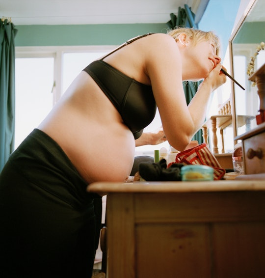Pregnant woman putting makeup on in bathroom