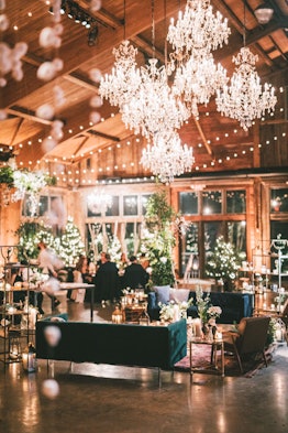 The inside of a wedding venue, with teal couches and various fairy light decorations in the middle o...