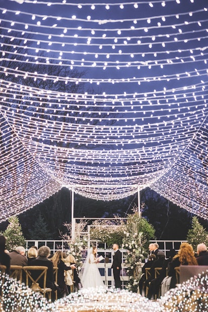 The bride and the groom on the isle with fairy light ceiling decorative elements in the middle of a ...