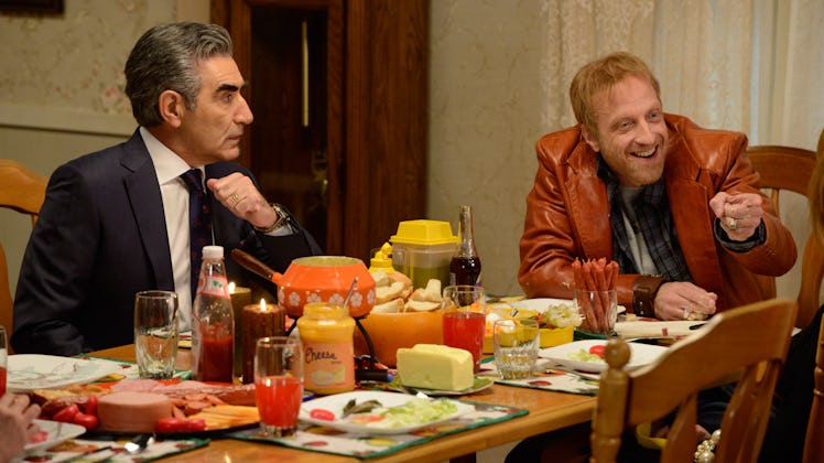 Roland Schitt and Johnny Rose sit a dining room table together for dinner in 'Schitt's Creek.'