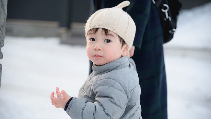 Toddler walking with a parent on the snow 