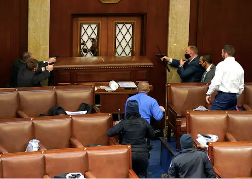 U.S. Capitol police officers point their guns at a door that was vandalized in the House chamber dur...