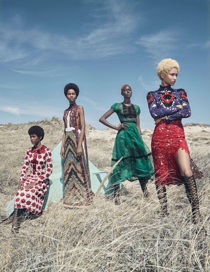 four models wearing dresses in a grassy field