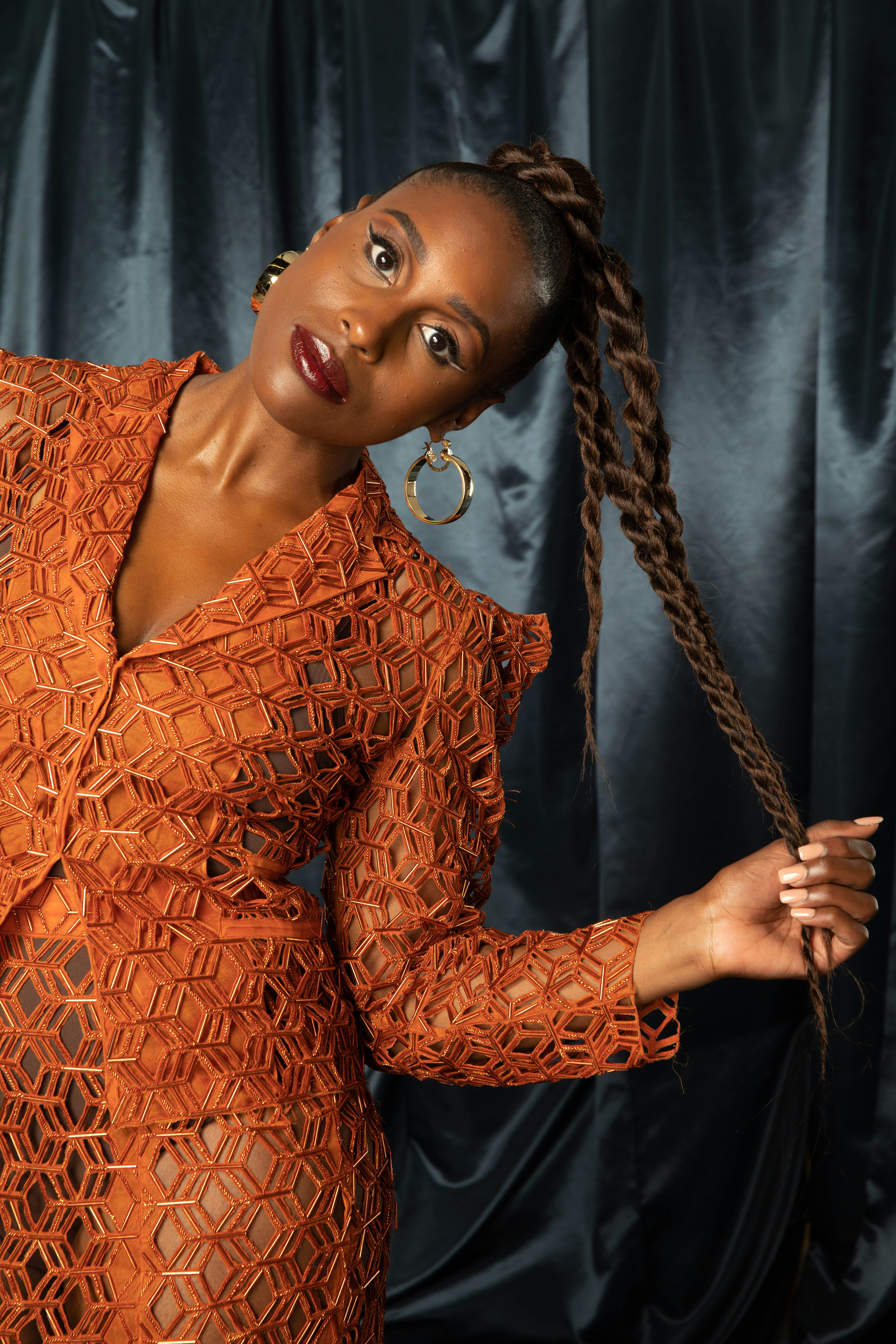 Issa Rae in an orange dress posing for The Good Ones Issue: The Voices that Made an Impact
