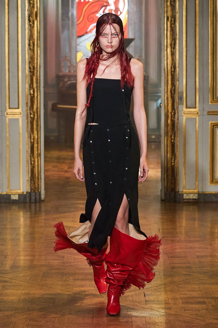 A model in Rochas spring 2022 collection black dress and red boots