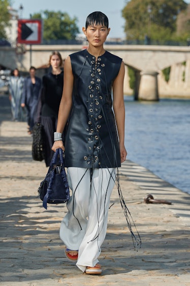 Model walking in a black dress and white pants at the Chloé fashion show at Paris Fashion Week Sprin...