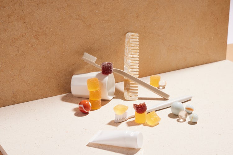  bathroom items, like a cup, toothbrush and a comb, artfully arranged with some gummies