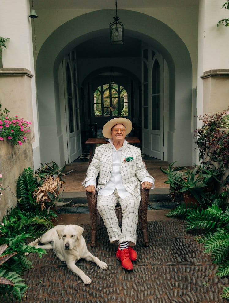 Manolo Blahnik, pictured with a dog, wears his own clothing and accessories.