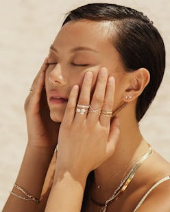 Models wears stacked rings, necklaces, and earrings from Aurate New York.