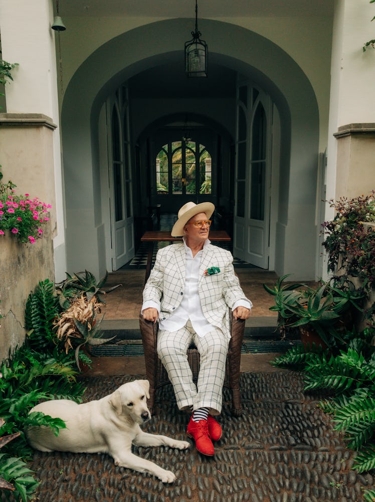 Manolo Blahnik, pictured with a dog, wears his own clothing and accessories.