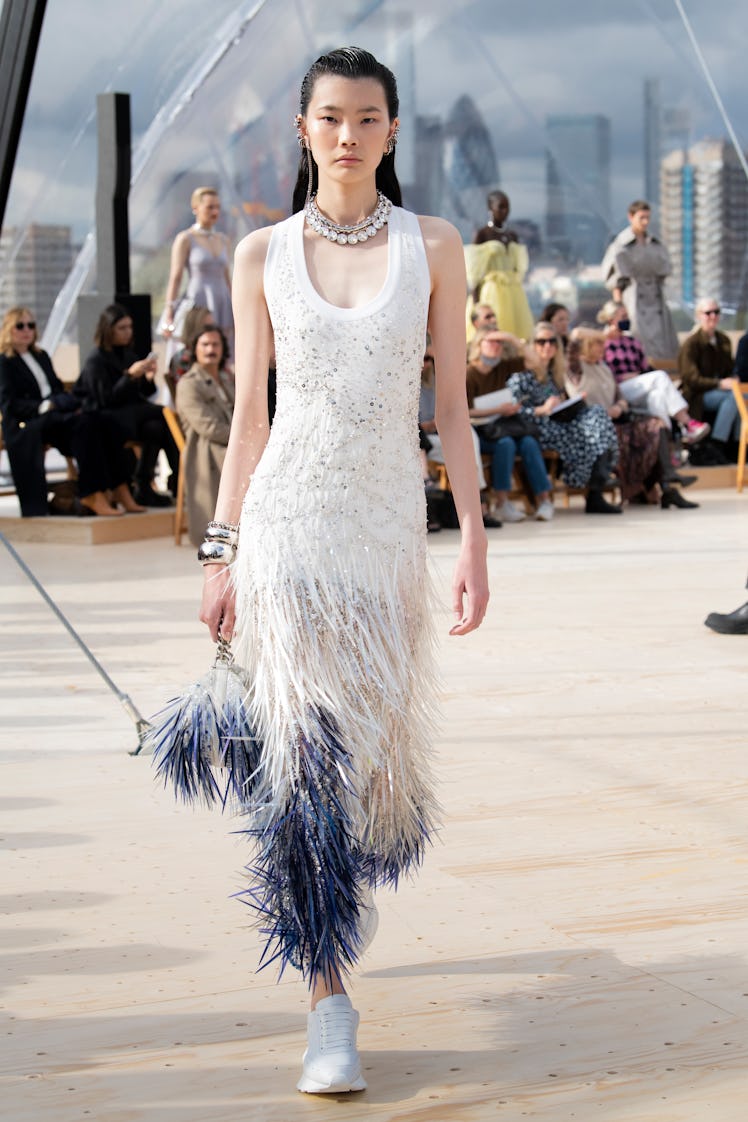 Model walking in a white feather dress at the Alexander McQueen Spring 2022 show.