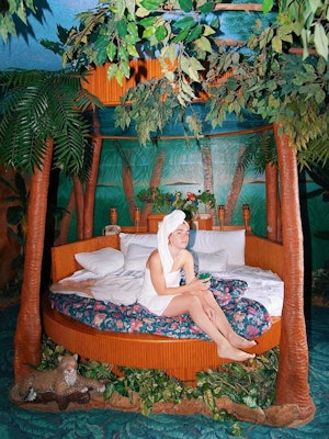 Margaret sitting in a palm-tree-themed bed with a towel on, at Cove Haven Resorts