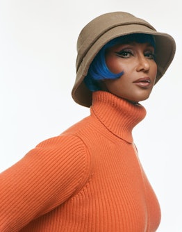 Iman in orange top and khaki hat.