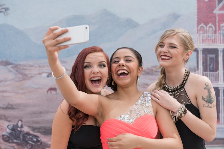 Young group of sorority sisters posing for a selfie at their college's fall semi-formal celebration,...