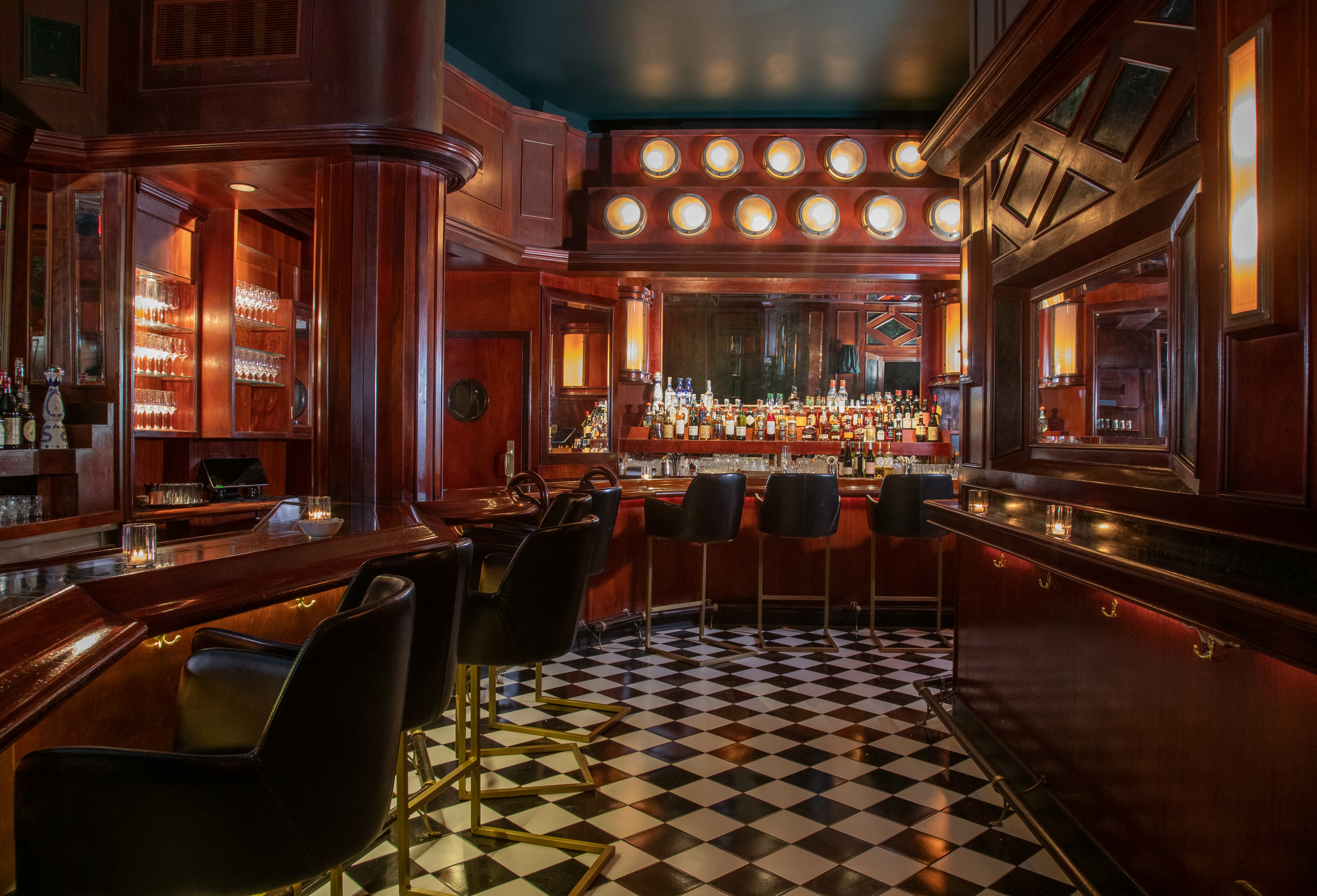 the inside of an old-fashioned bar, with wood panelling and black and white floors