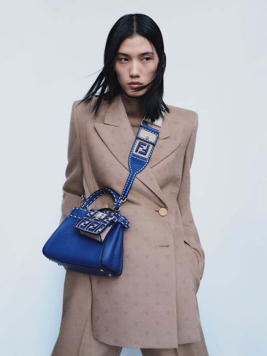A model wearing a tan Fendi jacket and a blue Fendi purse