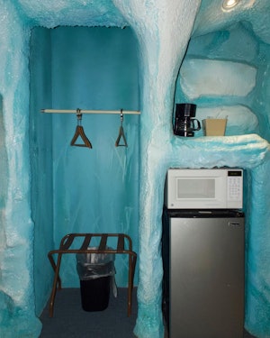 A fridge, microwave, coffee maker and hanger rack surrounded by ice at a hotel room 