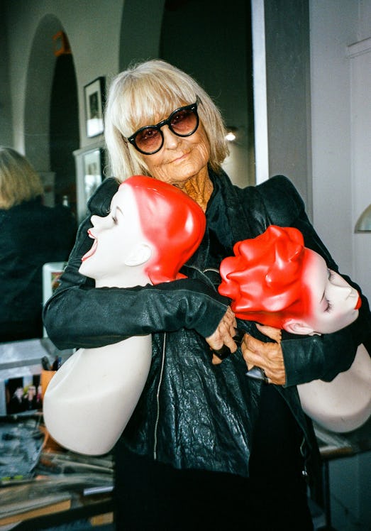 Barbara Hulanicki wears sunglasses holding two red-headed mannequin heads.