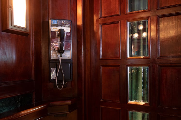 a pay phone in a wood panelled booth