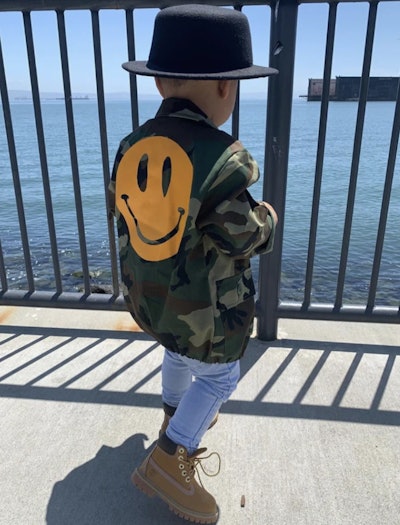Little kid modeling jacket with happy face on the back