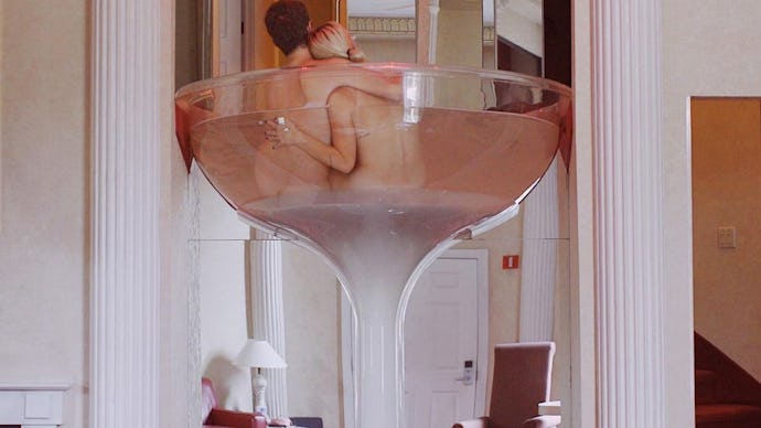  Margaret and Corey Bienert laying naked in an enlarged martini glass at a hotel 
