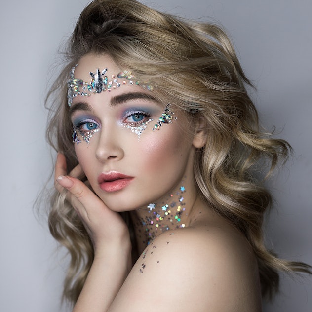 Woman looking at the camera with dramatic makeup and gems on her face