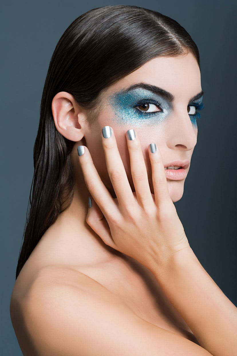 Woman looking at the camera, modeling dramatic blue eye makeup