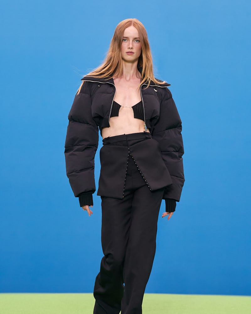Model wears gorpcore-inspired trousers and a black puffer jacket during Jaquemus' Fall/Winter 2021 r...
