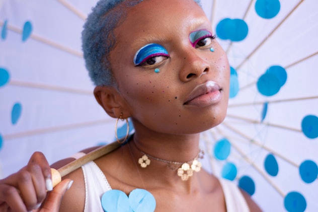 Black woman with blue hair and blue and pink makeup