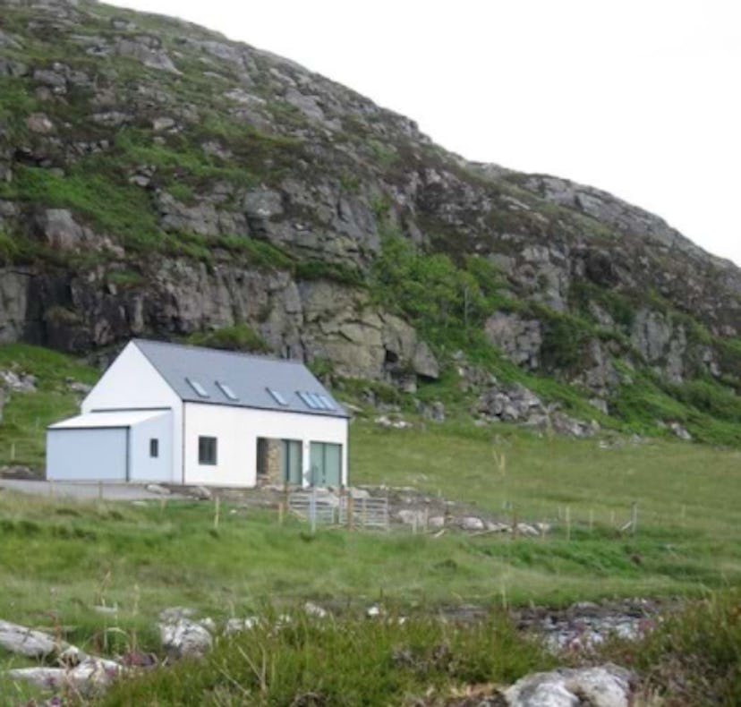 A white cabin with a sage green roof in Bernera, Outer Hebrides