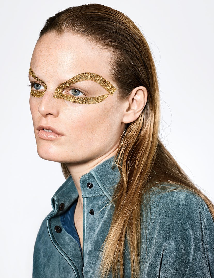 a model with a ring of gold glitter paint around her eye