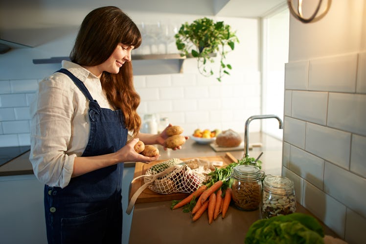 Young woman making potatoes on Thanksgiving 2021 after reading her horoscope.