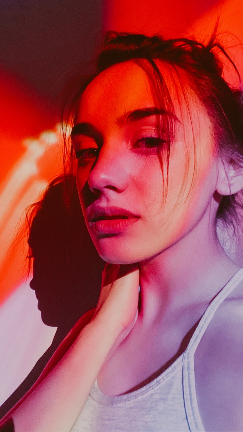 Young woman in neon red lights, her lucky color personality match for her zodiac sign.