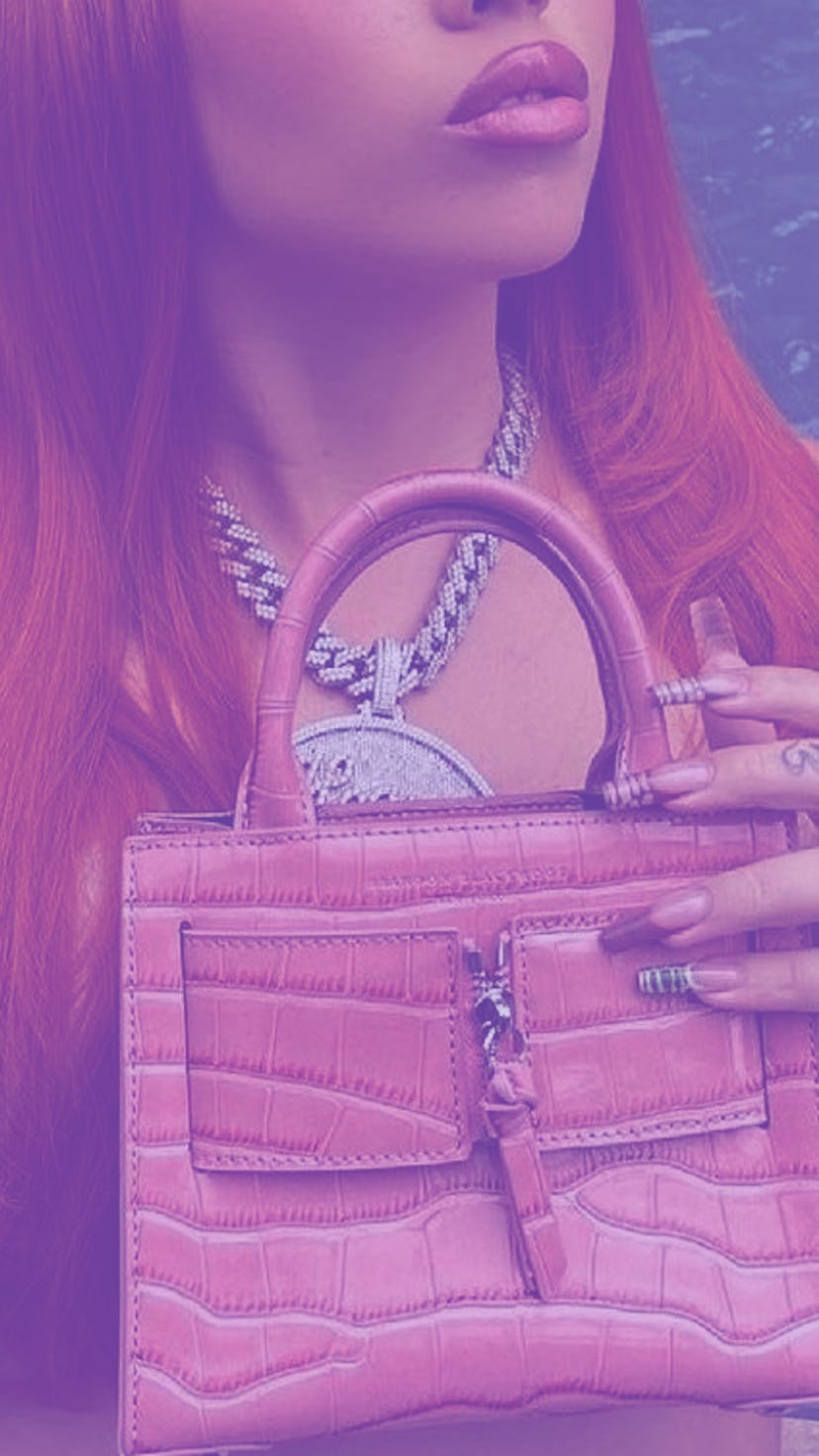 Woman with red hair, wearing a silver necklace, pink purse, and her nails manicured with crocodile n...