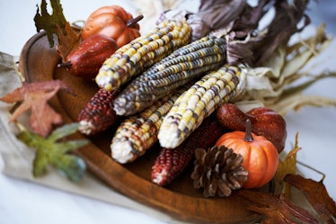 Table centerpiece with corn husks, pine cones, and pumpkins