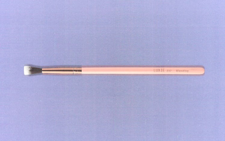 a pink makeup brush against a lavender background