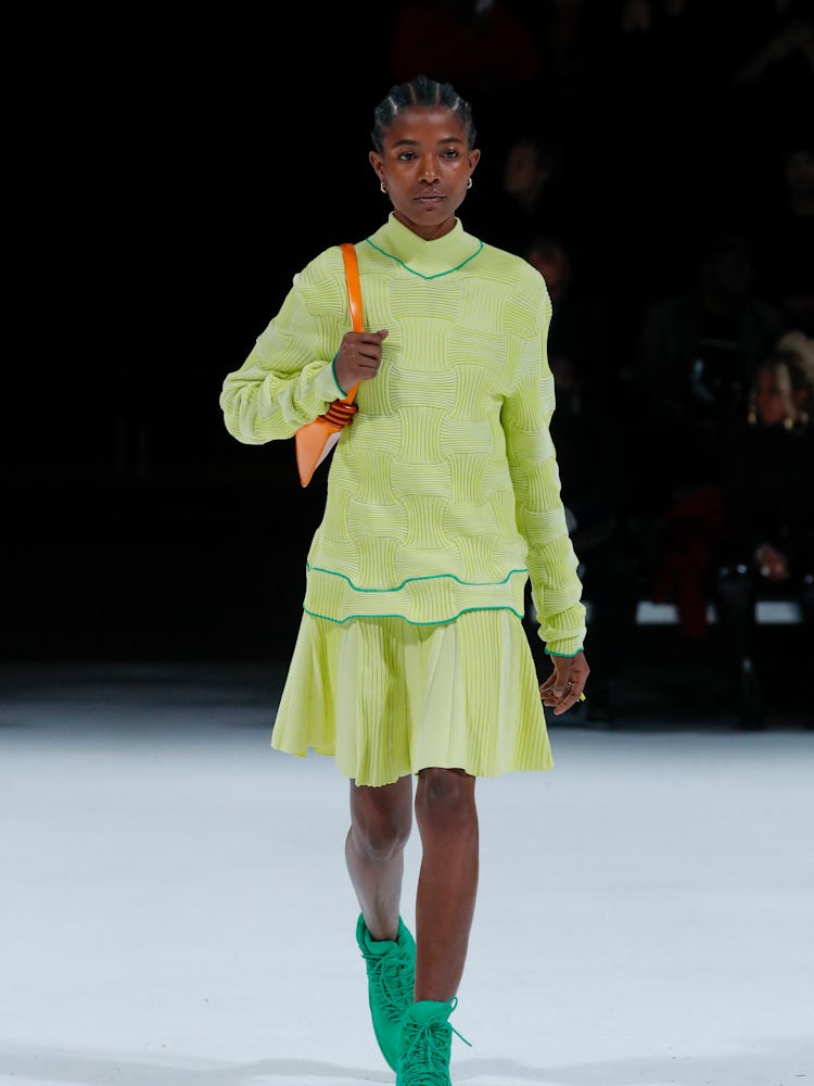 Model walking in a Bottega Veneta lime green skirt and shirt. 