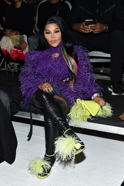 Lil Kim in a purple feathery dress and thigh-high leather boots with yellow feathers 