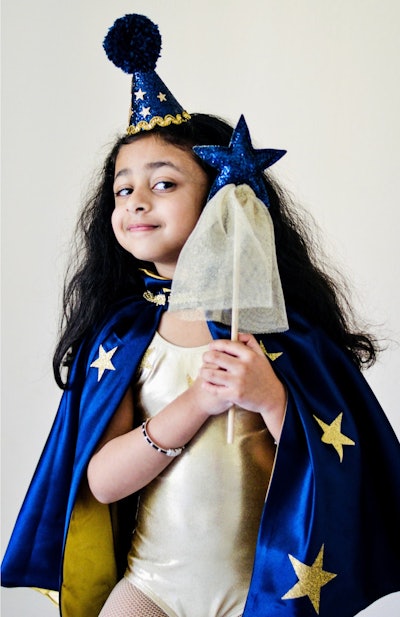 Little girl posing with wizard costume, hat, cape, magic wand; best gifts for 3-year-olds