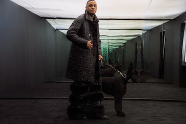 A model posing with a dog while wearing a Moose Knuckles x Telfar jacket 