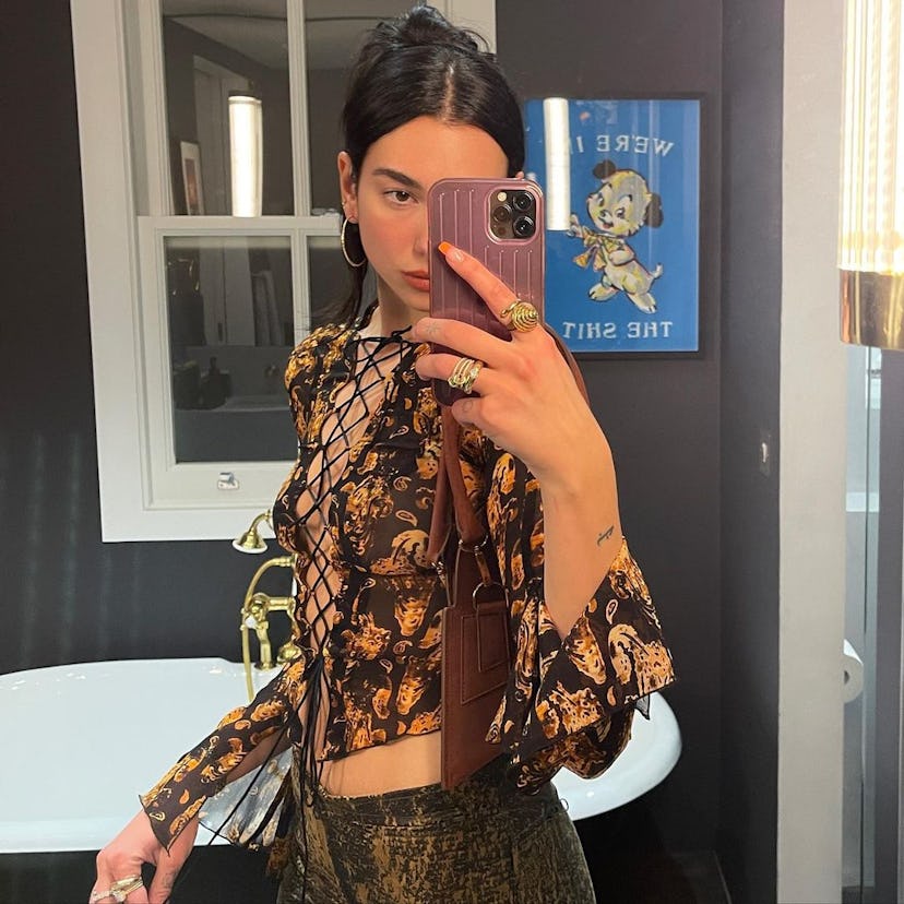 Dua Lipa taking mirror selfie with orange french manicure