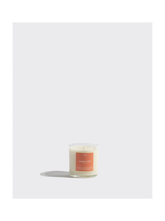 image of a scented candle with orange label and clear glass vessel
