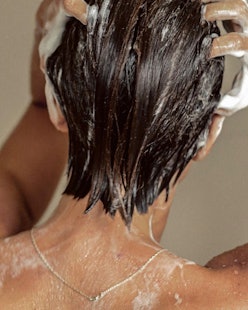 REVERIE model facing away from camera, washing hair in shower