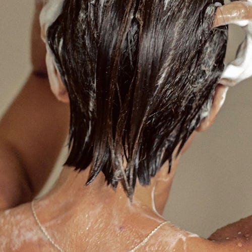 REVERIE model facing away from camera, washing hair in shower