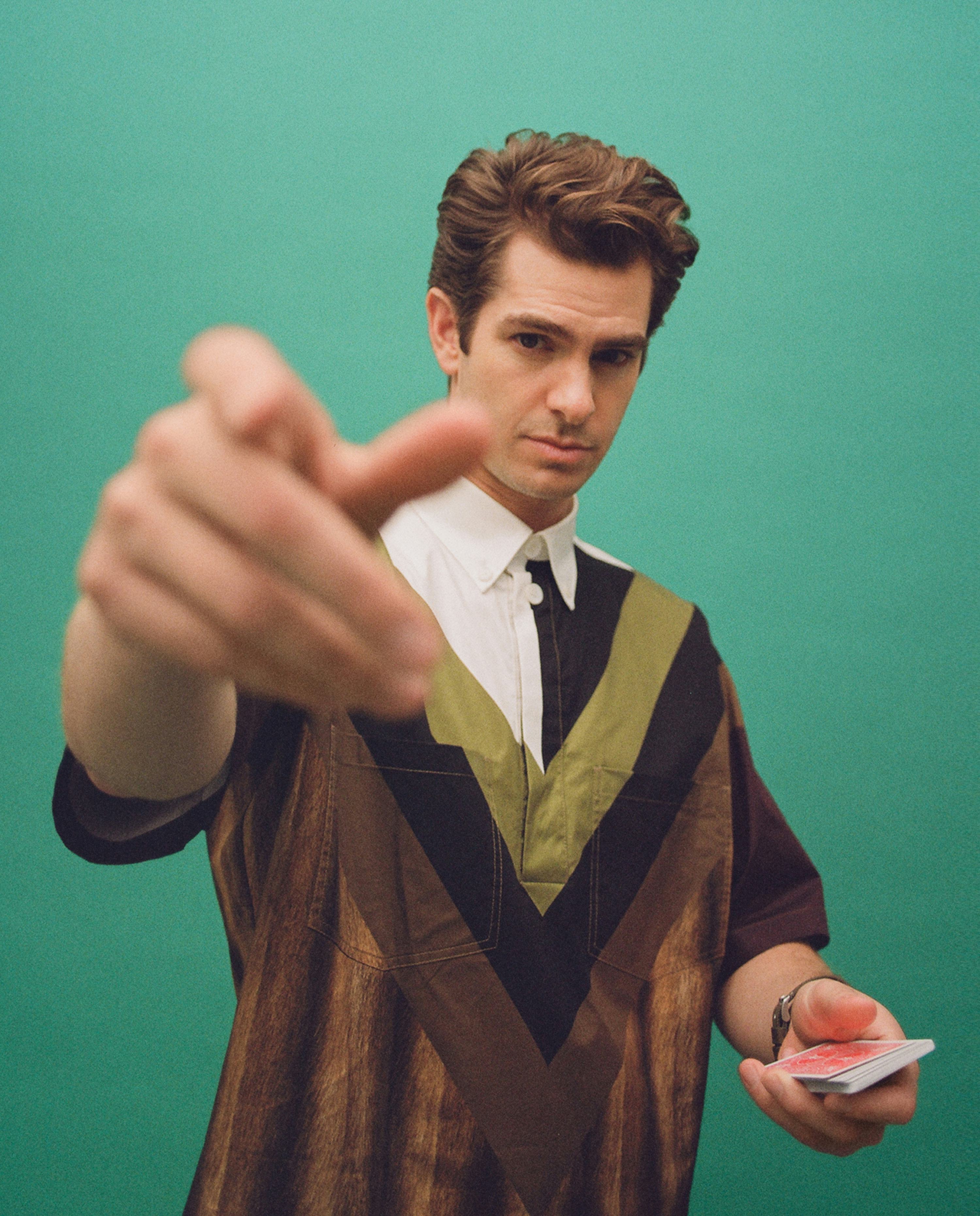 Andrew in a half-white, half-brown button-up with stripes of green and black holding up his right ha&hellip;