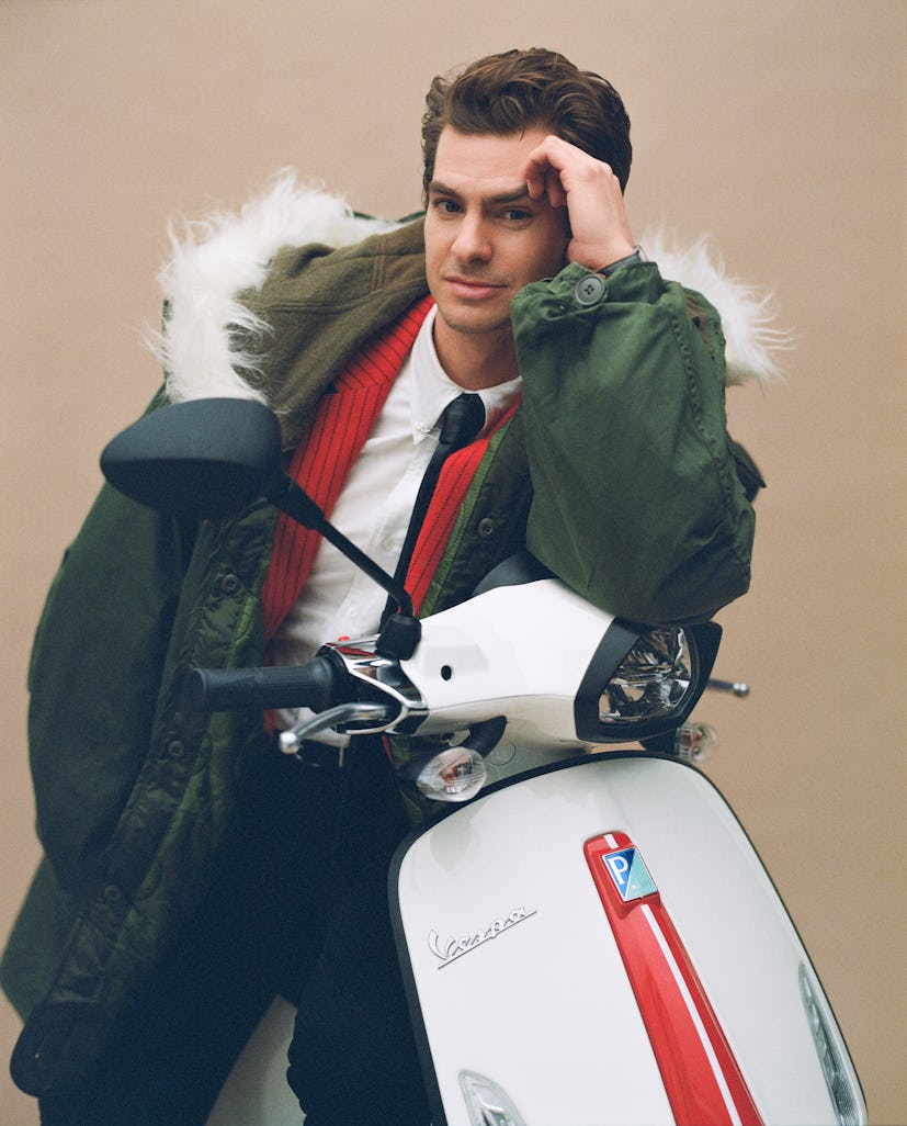 Andrew sitting on a white Vespa and wearing a vintage green parka 