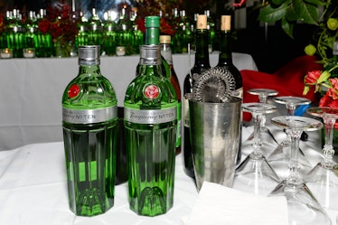 Bottles of Tanqueray gin, a cocktail mixing bottle and glasses on a table