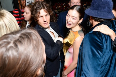 Theo Wenner in a black blazer and a white shirt and Lorde in a pastel dress with a gold top