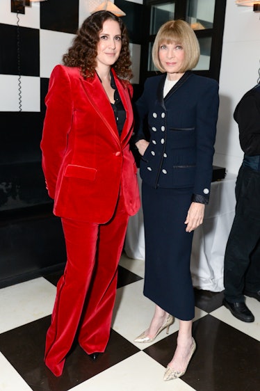 Sara Moonves in a red suit and a black shirt and Anna Wintour in a black blazer and skirt