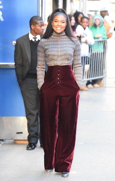 Gabrielle Union in a grey check turtleneck top and burgundy trousers